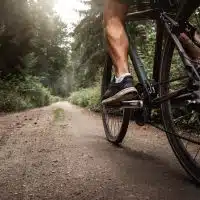 Cycliste roulant sur une route rurale en gravier, illustrant le potentiel du vélo comme mode de déplacement dans les territoires peu denses.