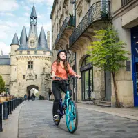 Cycliste roulant à vélo électrique dans une rue historique, illustrant les bienfaits du VAE sur le bien-être et la stimulation mentale.