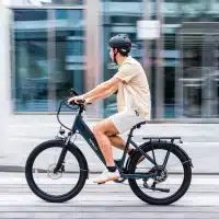 Cycliste portant un casque en milieu urbain, illustrant le débat sur la sécurité et le casque obligatoire à vélo.