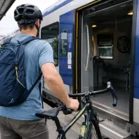 Cycliste montant dans un train TER avec son vélo sur un quai de gare en France