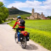 Cycliste en voyage à vélo traversant un paysage français avec village historique en arrière-plan