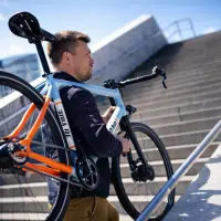 Homme portant un vélo électrique léger Electrolyte S4 E dans un escalier urbain