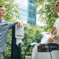 Couple rechargeant une voiture électrique sur une borne en environnement urbain