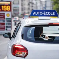 Voiture d’auto-école en formation sur route avec hausse du prix du carburant impactant le secteur