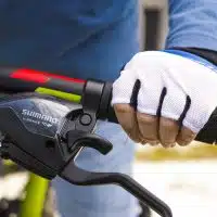 Main avec gant tenant un guidon de vélo équipé d’un frein Shimano