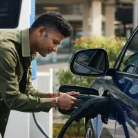 Conducteur branchant une voiture électrique sur une borne de recharge publique