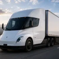 Tesla Semi roulant sur autoroute avec remorque dans un paysage montagneux