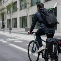 Cycliste urbain transportant du matériel de sport avec sacoches et sac à dos