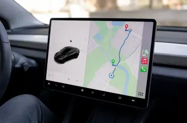 Interface Apple CarPlay sur écran central Tesla, affichant navigation et itinéraire de recharge